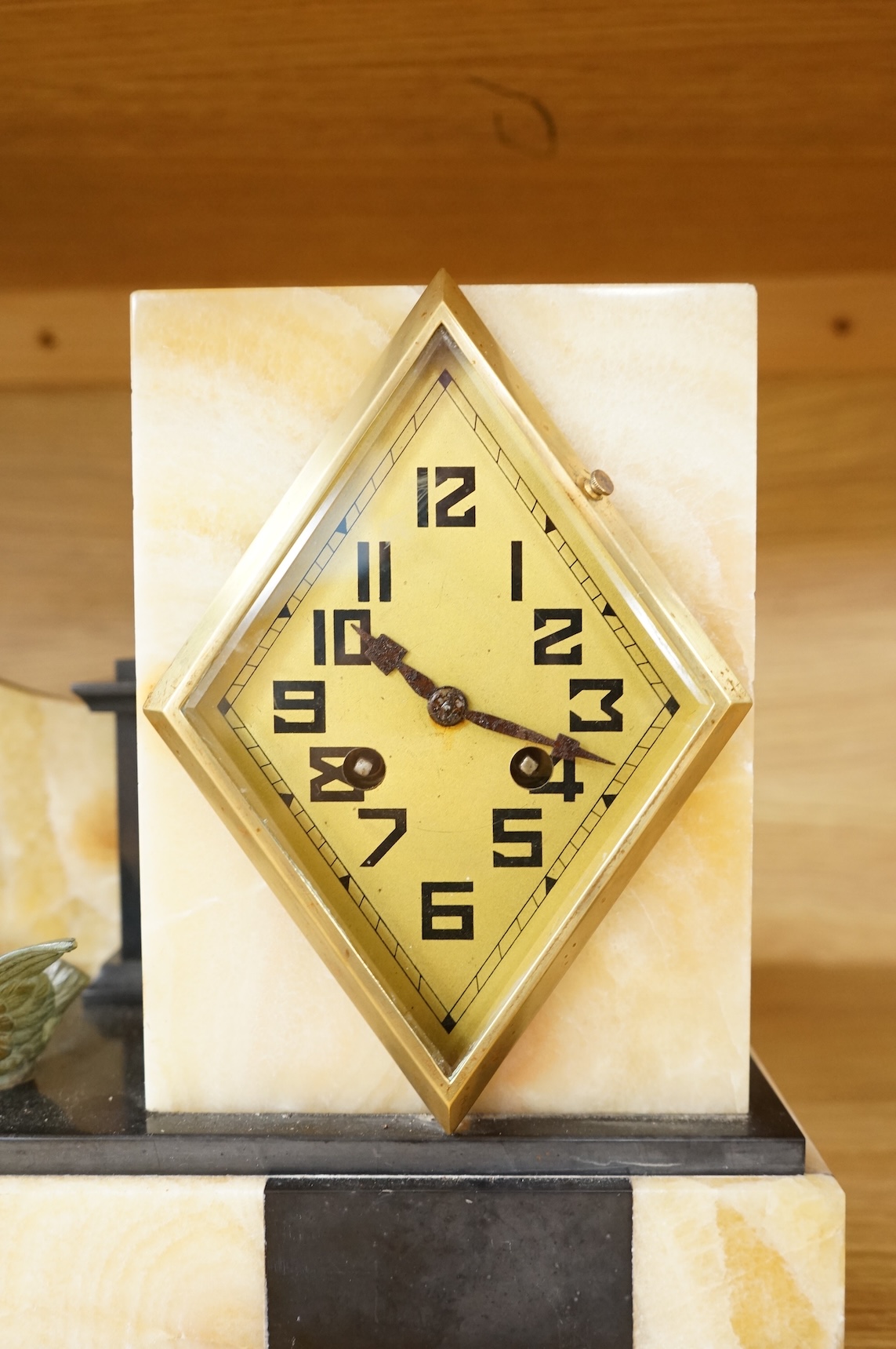 An Art Deco marble and slate clock garniture surmounted with a woman and birds, 52cm wide
